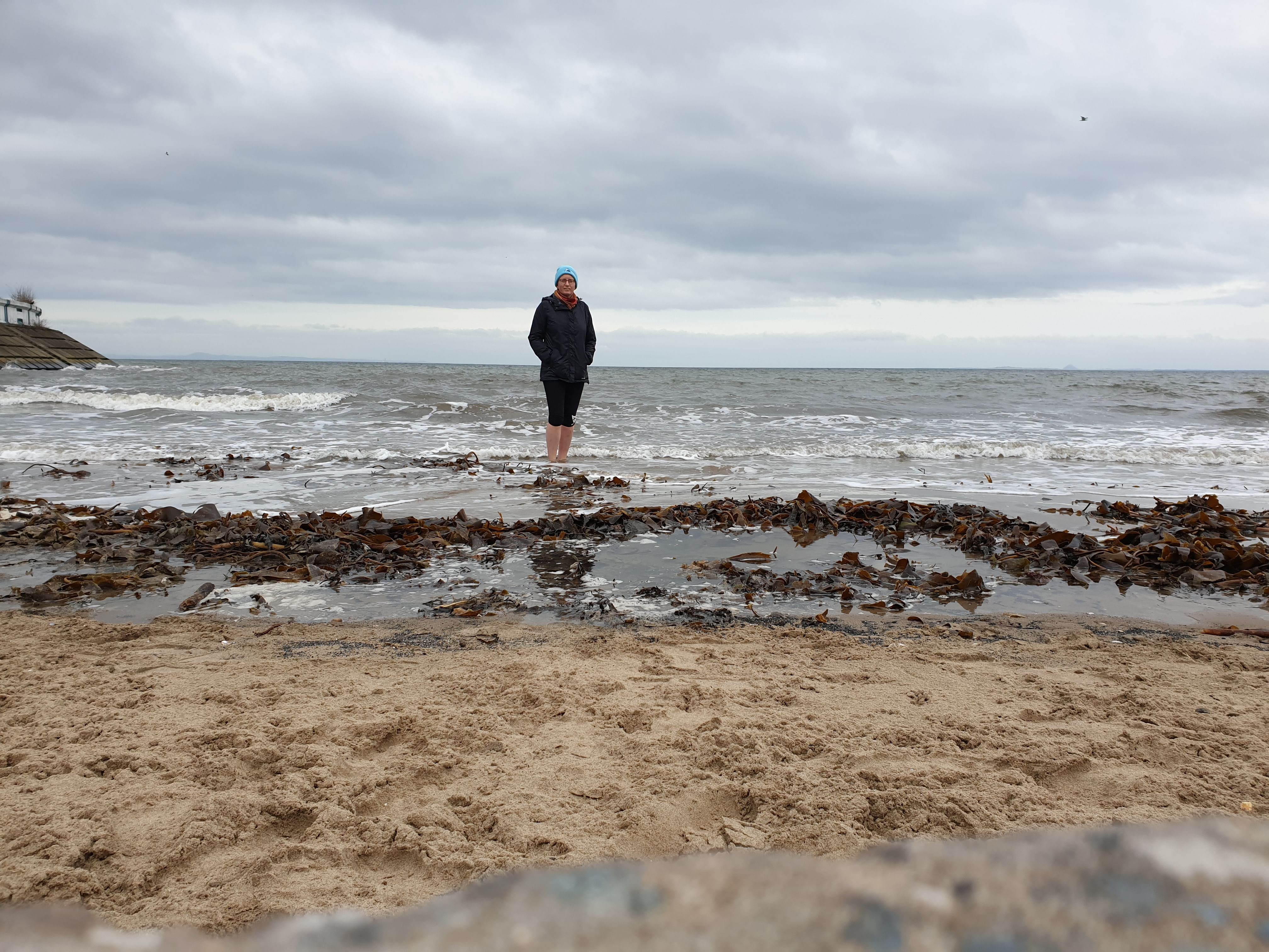 Dr. Eleanor Harris positioned on a beach as the waves coming in behind her